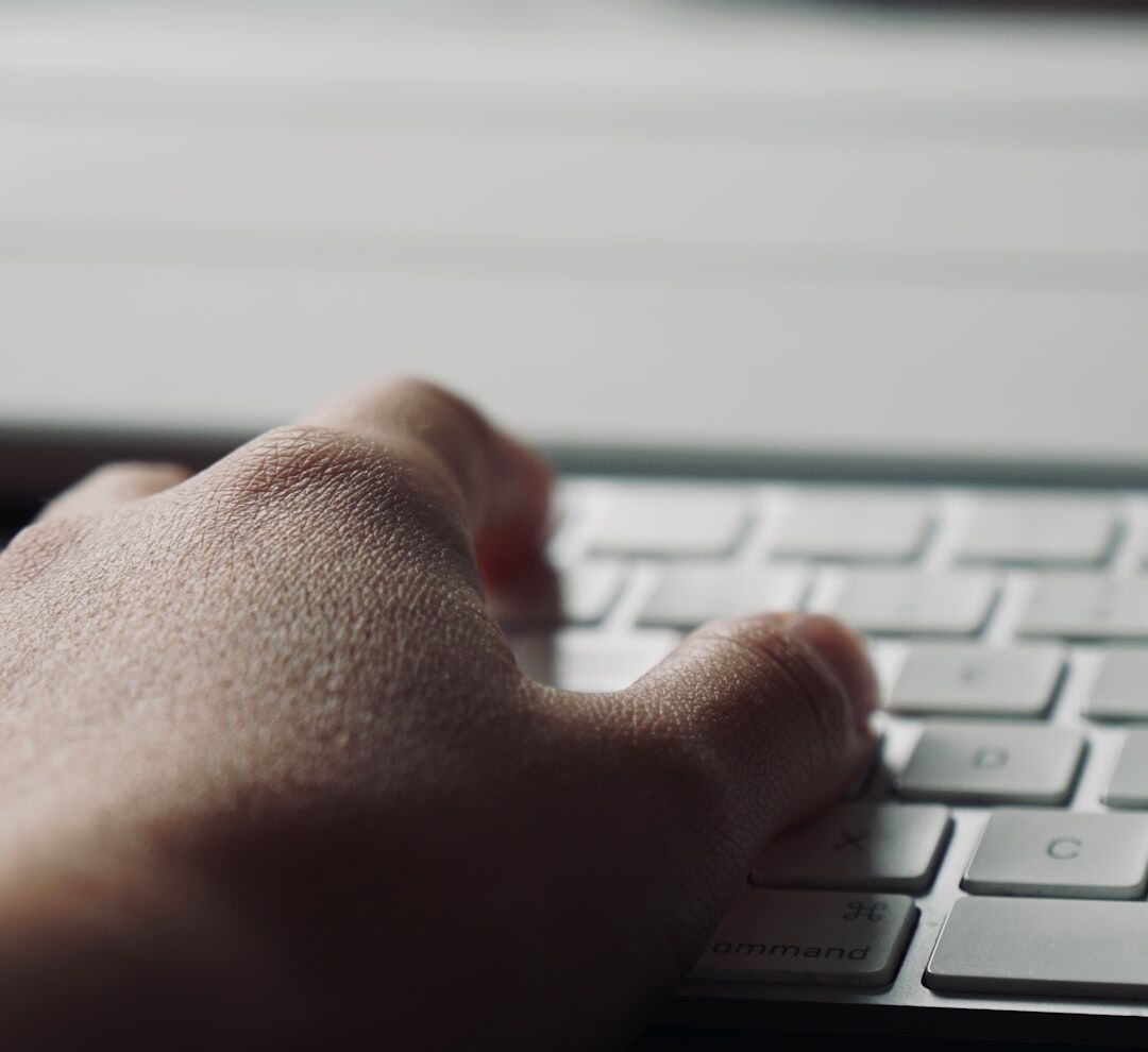 Close-up of hands typing on a keyboard with a news website on screen